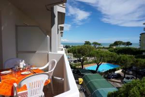een balkon met een tafel en stoelen en een zwembad bij Ideal flat near the beach - Beahost Rentals in Porto Santa Margherita di Caorle