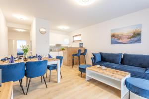 een woonkamer met een blauwe bank en een tafel en stoelen bij Ambria Apartments Platan Complex II in Świnoujście