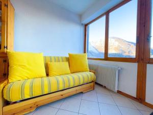 a couch with yellow pillows in a room with a window at 150m DALLE PISTE - Parcheggio Gratis in Sella della Turra