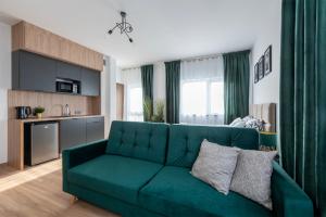 sala de estar con sofá verde y cocina en Apartamenty RIO Skarbimierz-Osiedle en Skarbimierz Osiedle