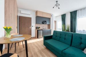 Apartamenty RIO Skarbimierz-Osiedle في Skarbimierz Osiedle: غرفة معيشة مع أريكة خضراء وطاولة