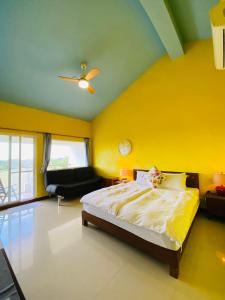 1 dormitorio con cama y pared amarilla en Kenting COMIC B&B, en Hengchun