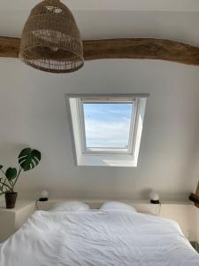 um quarto com uma cama branca e uma janela em Appartement cosy et lumineux au cœur de Montreuil em Montreuil-sur-Mer