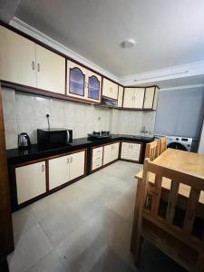 a kitchen with white cabinets and a wooden table at Newa service apartment in Pātan