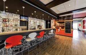 a restaurant with red chairs and a bar at ibis München Parkstadt Schwabing in Munich