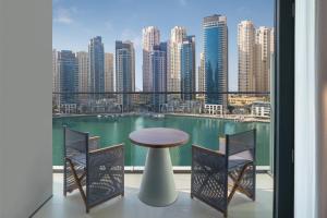 Vida Dubai Marina & Yacht Club في دبي: بلكونه مع طاوله وكراسي واطلاله على مدينه