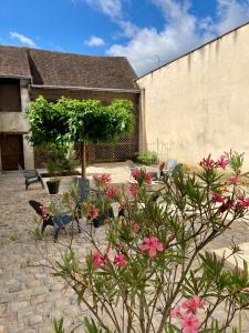 a courtyard with flowers and chairs and a building at La maison Virginie log 1 à 2 pers charmant hyper centre parking linge wifi proximité lac canal piscine in Montargis