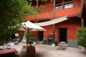 a patio with an umbrella and chairs and a building at El Cocheron 1919 in Aranjuez