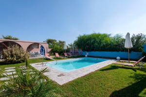 a swimming pool in a yard with chairs and an umbrella at Afandou Beach Villas Sofias in Afantou