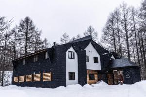 a black and white house in the snow at Onpoint Madarao in Myoko