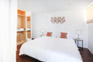 a white bedroom with a large white bed at Santa Joana Apartments with garden and heated pool in Lisbon