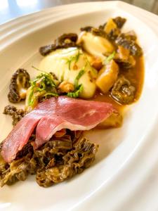 a white plate of food with meat and mushrooms at Hostellerie Du Chateau in Châteauneuf