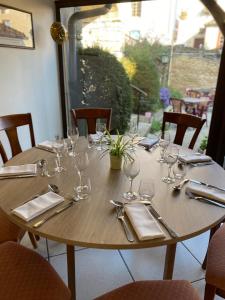 - une table en bois avec des verres à vin et de l'argenterie dans l'établissement Hostellerie Du Chateau, à Châteauneuf