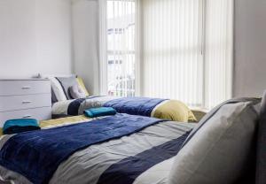 a bedroom with three beds with blue and yellow sheets at Large 4 Bed, En Suite Free Parking in Walton on the Hill