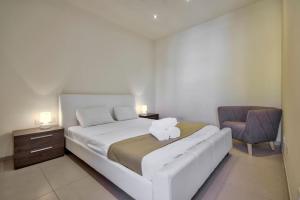- une chambre avec un grand lit blanc et une chaise dans l'établissement Lucky Star 103 by Vallettastay, à La Valette