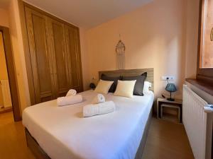 a bedroom with a large white bed with two towels at Apartamento Hasta 4 Pax con Terraza in Soldeu