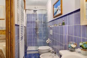 La salle de bains est pourvue de carrelage bleu, de toilettes et d'une douche. dans l'établissement Ca' La Vedescia App Mantaula, à Teglio