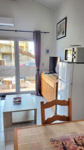 een keuken met een koelkast en een tafel en een tafel bij Maison 100m de la plage avec parking securise plus fibre optique internet in Valras-Plage