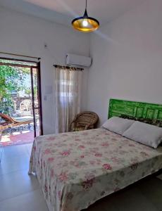 a bedroom with a bed with a green headboard at Amarelo Hibisco in Guarda do Embaú