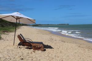 a chair and an umbrella on a beach at Pousada Colmeia - Praia de Santo André, Bahia in Santo André