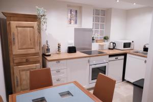 a kitchen with white cabinets and a table with chairs at Gîte le petit écolier in Lectoure