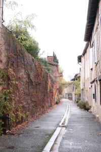 an empty street next to a stone wall at Gîte le petit écolier in Lectoure