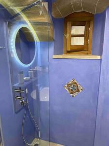 niebieska łazienka z prysznicem i lustrem w obiekcie MONOVASIA SUITES Anopolis w mieście Monemwasia