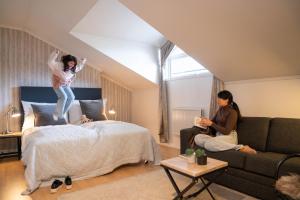 uma rapariga a saltar para uma cama numa sala de estar em Lampeland Hotel em Lampeland