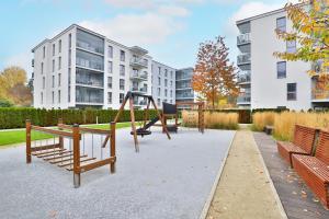a playground with benches and a swing at Gdańsk Krasickiego Apartments by the Beach by Renters in Gdańsk
