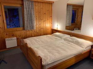 1 dormitorio con 1 cama grande y espejo en Les Bouquetins, en Zinal