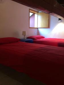 a bedroom with two beds with red sheets and a window at Holiday House La Colombaia in Parma