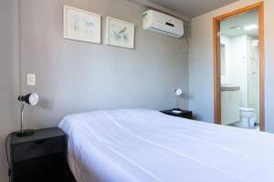 a bedroom with a white bed and a bathroom at Praia Central Porto de Galinhas in Porto De Galinhas