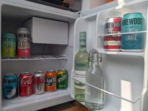 - un réfrigérateur ouvert avec des canettes et une bouteille de soda dans l'établissement *Large Unique Retro Private Attic & Bathroom*, à Brighton et Hove