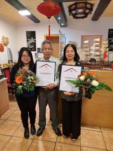 a group of three people holding up certificates at Pension an der Stadtmauer in Wernigerode