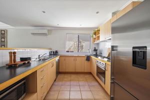 a large kitchen with wooden cabinets and stainless steel appliances at Villa 11 Margaret River Beach House in Margaret River Town