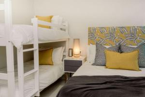 a bedroom with a white bunk bed and yellow pillows at Newly renovated stylish Mallorca Apartment in Umdloti +21 photos