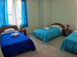 a bedroom with two beds with blue sheets and blue curtains at El Paraiso in Puerto Ayora