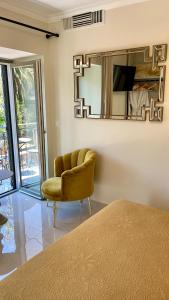 1 dormitorio con silla amarilla y espejo en Aesthesis Arxontiko Luxury Rooms, en Mirina