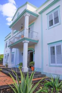 a white house with a balcony and plants at Bella Italia Populo Guest House in Ponta Delgada