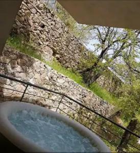 una vasca da bagno di fronte a un muro di pietra di Maison avec jacuzzi au cœur des montagnes a Feliceto