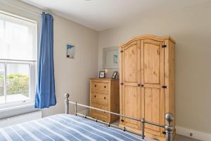 a bedroom with a wooden cabinet and a bed at Middle Deal Cottage in Deal