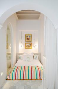 a white bedroom with a bed with a colorful blanket at Dar Dorra in Tunis