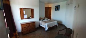 1 dormitorio con cama, tocador y espejo en Cabañas Telayú en Mazunte