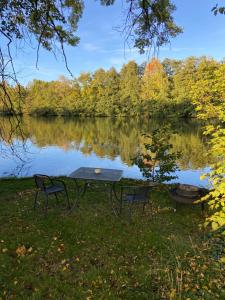 a picnic table and two chairs in front of a lake at Seeblick Apartments Mühlau in Mühlau