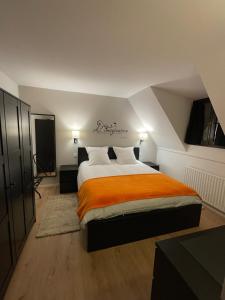 a bedroom with a large bed with an orange blanket at Le 6B in Hoenheim