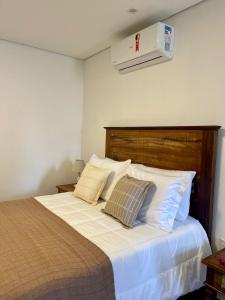 um quarto com uma cama com lençóis brancos e almofadas em Pousada Villa Tiradentes em Tiradentes