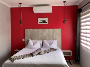 a bedroom with a red wall and a white bed at Rhino House with 3 bedrooms next to Pilanesberg and Sun City in Mogwase