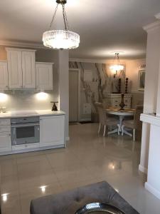 eine Küche und ein Wohnzimmer mit weißen Schränken und einem Tisch in der Unterkunft Apartament Parys Gold in Malbork