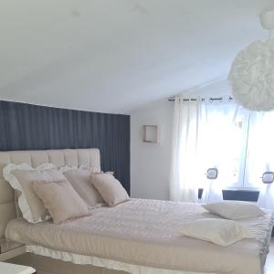 um quarto branco com uma cama grande e almofadas brancas em la perle blanche em Spa