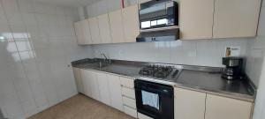 a small kitchen with a stove and a microwave at Apartamento Sector Colores - Estadio in Medellín